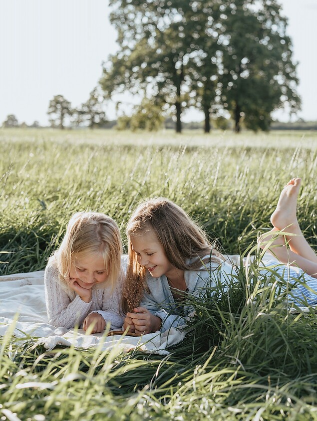 Zwei Mädchen liegen im Gras