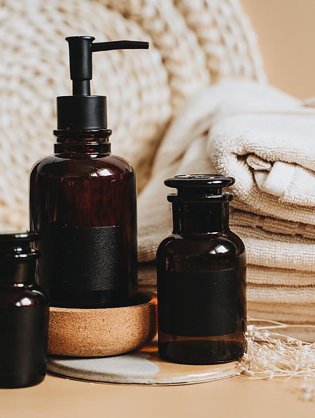 Kleine Kosmetikfläschchen und gerollte Handtücher als Detail im Wellnessbereich