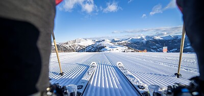 Skifahrer mit Blick auf perfekt präparierte Piste und verschneite Berge in Bad Kleinkirchheim.