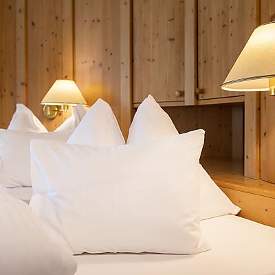 Gemütliches Bett aus Naturholz mit weichen Kissen im Naturhotel Eschenhof.