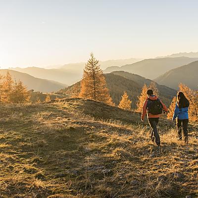 Ein Paar wandert durch die bunten Wälder im Thermenherbst in Bad Kleinkirchheim