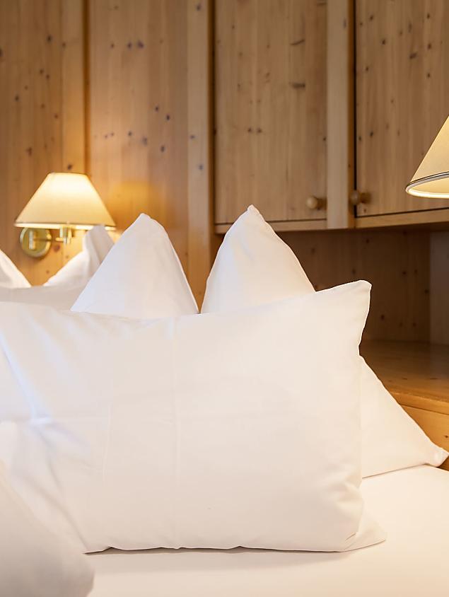 Gemütliches Bett aus Naturholz mit weichen Kissen im Naturhotel Eschenhof.